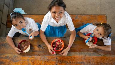 Dana (center), Ashly Nayeli (left) and Anyeli Sofia (right) sit together to eat the hot school meal: red bean soup.