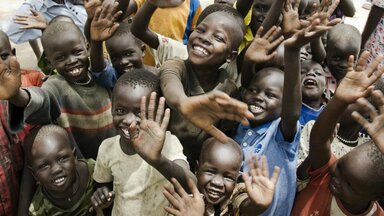 group of kids smiling at waving at the camera in South Sudan